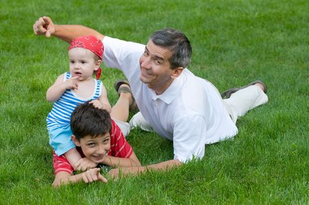 a father and his sons are playing on the grass in the parkの写真素材