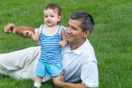 a father and his son are playing on the grass in the parkの写真素材