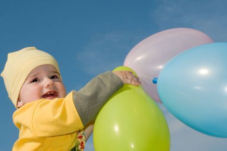 a baby is playing with multicolored balloonsの写真素材
