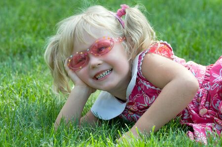 a little girl is lying on the grass in the parkの写真素材