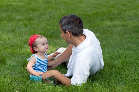 a father and his son are playing on the grass in the parkの写真素材