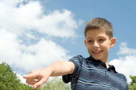 teen is pointing a distant object while walking outdoorsの写真素材