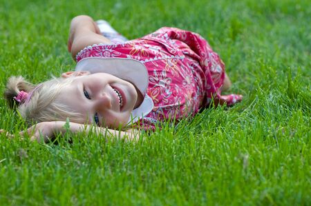 a little girl is lying on the grass in the parkの写真素材
