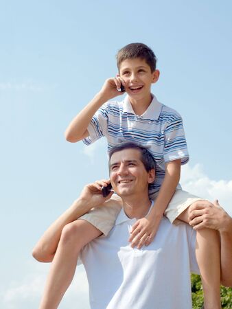 a father and his son are loking forward and speaking over mobilesの写真素材
