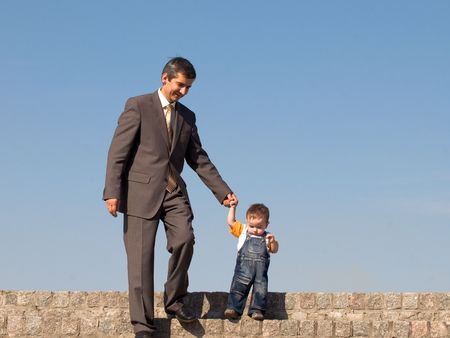 a father and his little son are walking outdoorsの写真素材