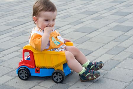 a serious baby boy is sitting in the toy truckの写真素材