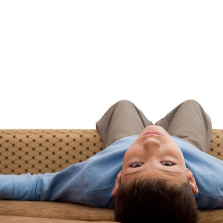 a boy in blue pullower is lying upside down on the sodaの写真素材