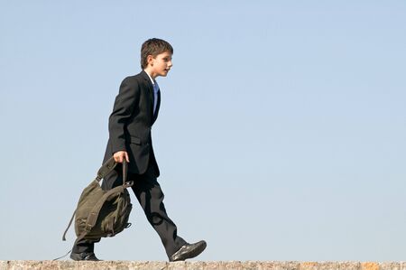 a successful school student is walking home holding his schoolbag in his handsの写真素材