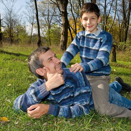 a son is playing with his dad in the autumn parkの写真素材