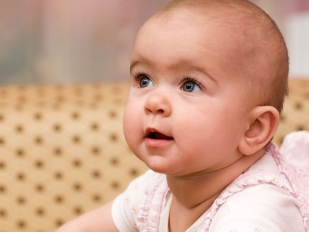 a portrait of a baby in pink suit on the sofaの写真素材