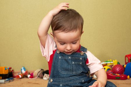 A thoughtful baby boy is playing with toysの写真素材