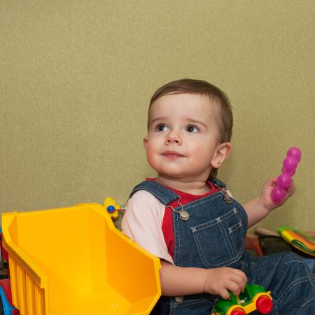 A baby has got his aim while playing toy trucksの写真素材