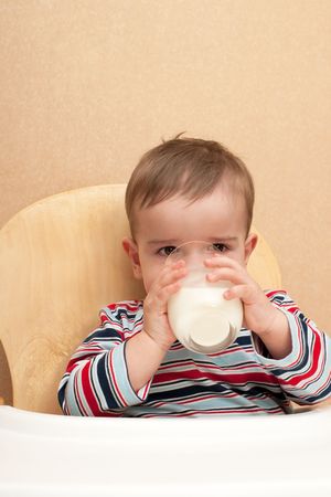 A toddler is drinking a glass of milkの写真素材