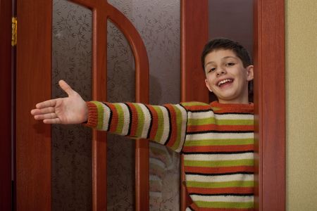 A laughing boy is inviting guests in the doorwayの写真素材