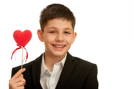 A smiling boy is showing a red heart; isolated on the white backgroundの写真素材