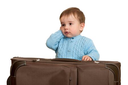 A toddler is talking over the phone while packing a suitcase; isolated on the white backgroundの写真素材