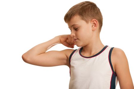 A kid is checking his muscules growth while doing his morning exercises; isolated on the white backgroundの写真素材