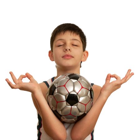A kid is meditating holding a football ball in his armsの写真素材