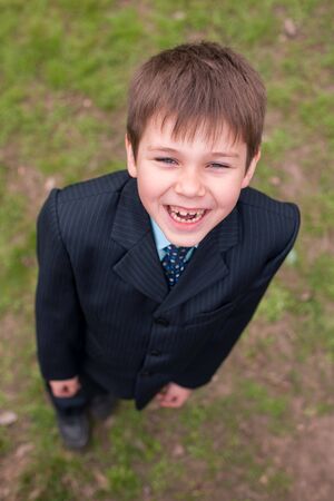 A smiling boy in suit is standing on the spring meadowの写真素材
