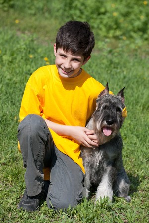 A boy is hugging his pet walking outdoorsの写真素材