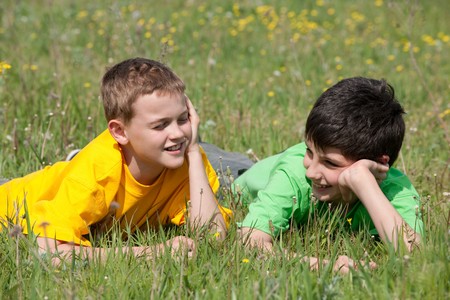 Two boys are having a conversation outdoors on the grassの写真素材