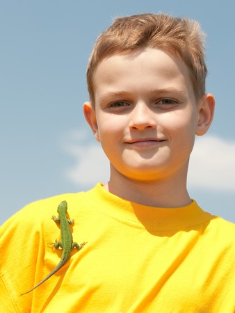 A lizard is on the shoulder of a smiling boy in yellou shirtの写真素材