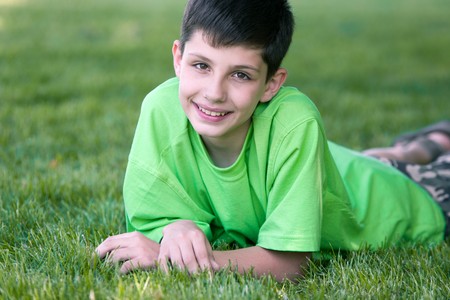 A boy in green is lying on the meadowの写真素材