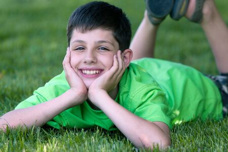 A boy in green is lying on the grassの写真素材