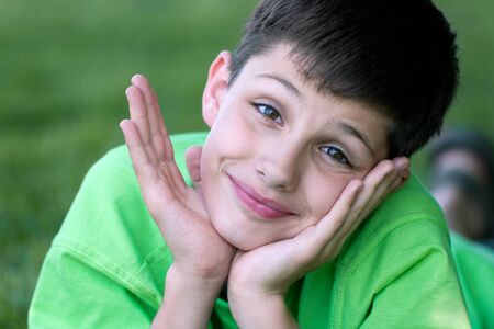 A portrait of a boy in green lying on the gladeの写真素材