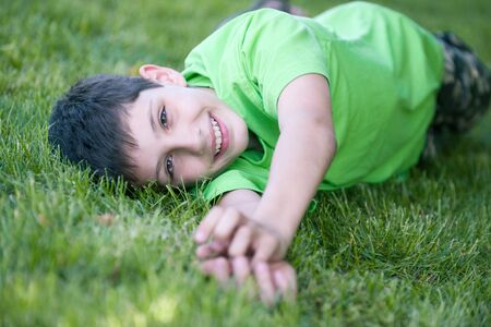 Happy boy in green is lying on the summer meadowの写真素材
