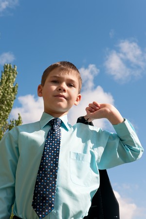 A serious boy in tie is fastening his jacketの写真素材