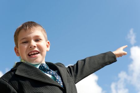 A laughing boy in black suit is pointing forwardの写真素材