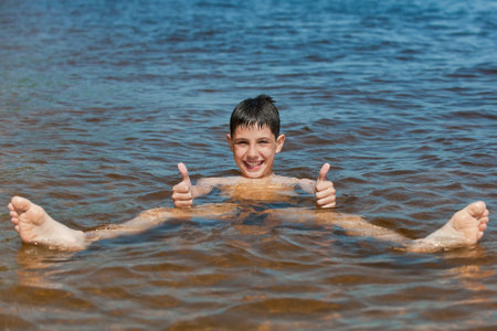 A swimming boy is holding his thumbs up の写真素材