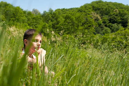 A thoughtful  boy is sitting in the green fieldの写真素材