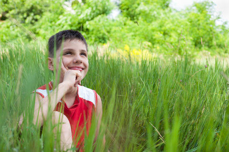 A smiling boy is sitting in the green grassの写真素材