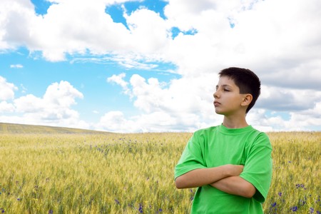 A thoughtful boy is standing in the field of wheatの写真素材