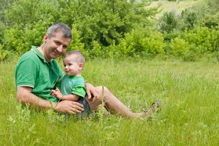 A father and his little son are sitting outdoor togetherの写真素材