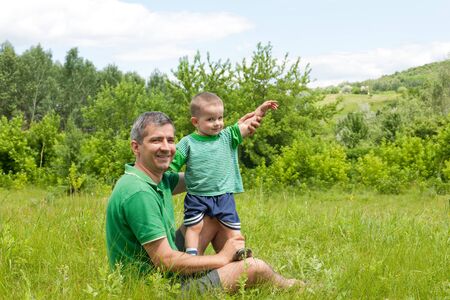 A happy father and his little son are sitting outdoor togetherの写真素材