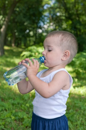 A little boy is drinking water outdoorsの写真素材