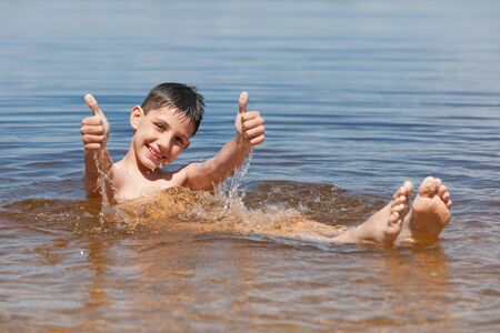 A happy swimming boy is holding his thumbs upの写真素材