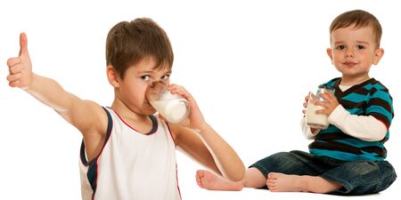 Two children are drinking milk; isolated on the white backgroundの写真素材