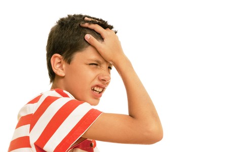 A boy suffer  with a headache is holding his head; isolated on the white backgroundの写真素材