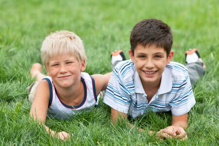 Two friendly handsome boys are lying on the grassの写真素材