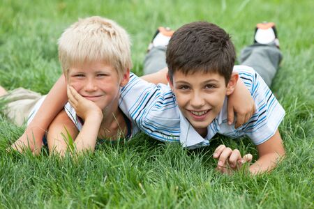 Two friendly boys are lying on the green grass の写真素材