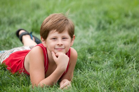 A dreaming boy is lying on the green grassの写真素材