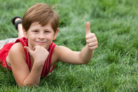 A smiling boy is lying on the green grassの写真素材