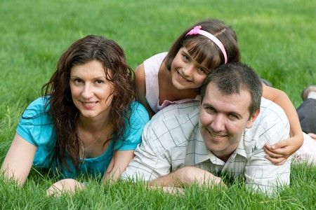 Father, mother and their daughter are lying on the summer meadowの写真素材