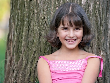 A portrait of a pretty smiling girl in summer shirt against the treeの写真素材