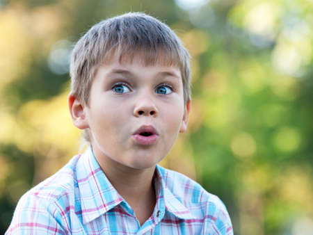 A portrait of a  surprised boy in the autumn parkの写真素材