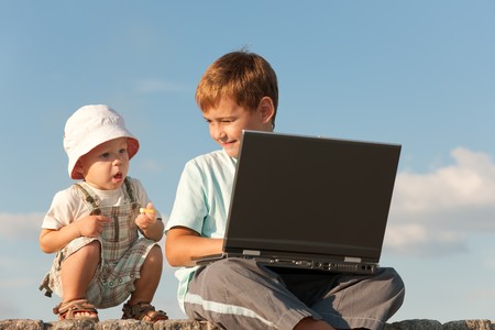 Two brothers are learning using a laptop outsideの写真素材